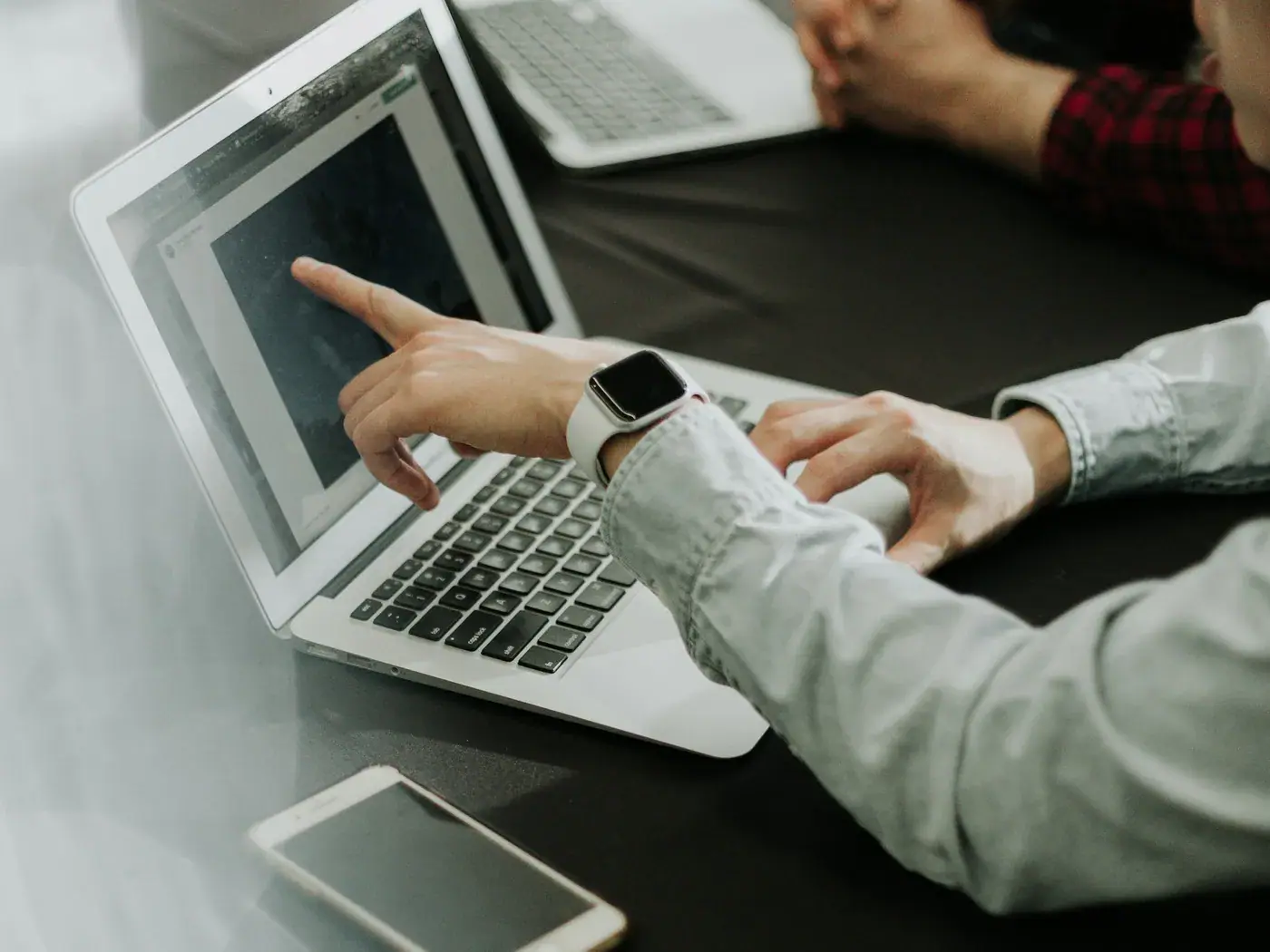 Deux collaborateurs analysent des chiffres sur un ordinateur portable, au bureau.