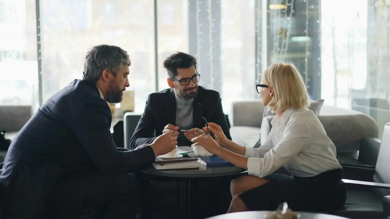 Trois dirigeants en discussion autour d’une table ronde, dans un bureau lumineux