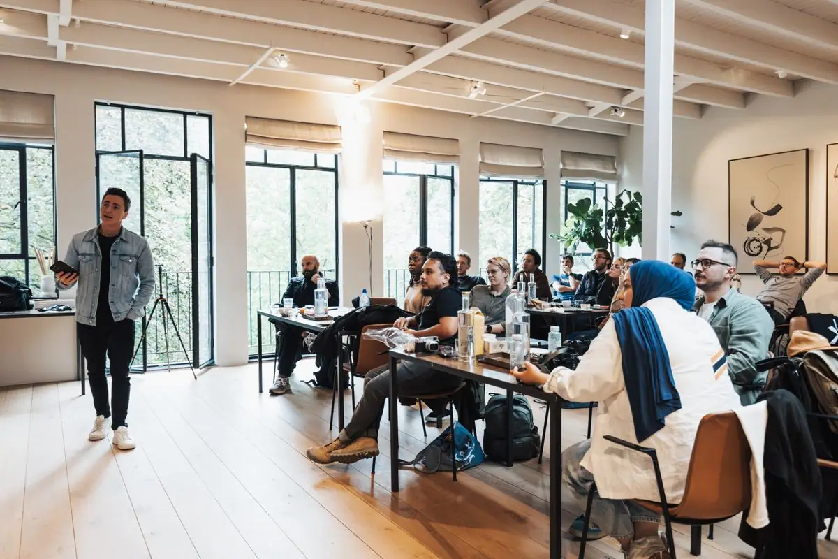 Un formateur debout face à des participants de profils variés, dans une salle de formation lumineuse