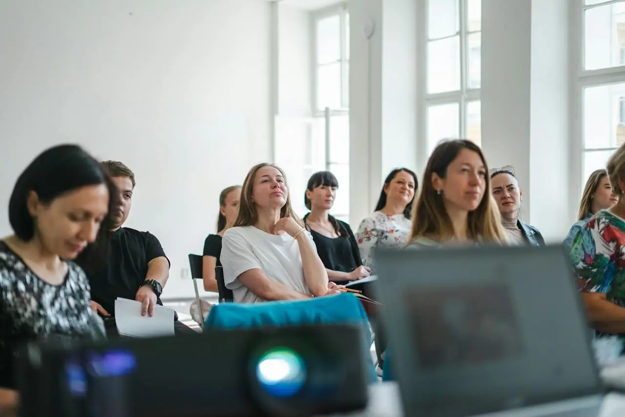 Un groupe d'adultes attentifs pendant une session de formation, dans une salle baignée de lumière
