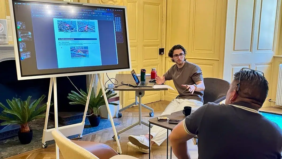 Séance de formation : le formateur commente un document projeté sur grand écran face à un participant.