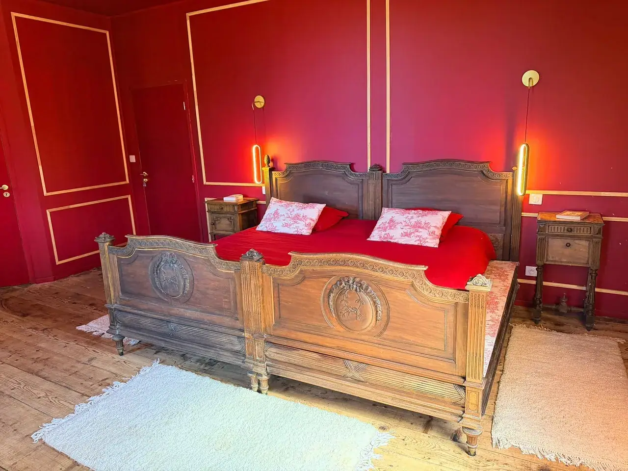 La Suite du Roi et de la Reine, au Domaine d’Éden : murs rouges et lit ancien en bois sculpté.