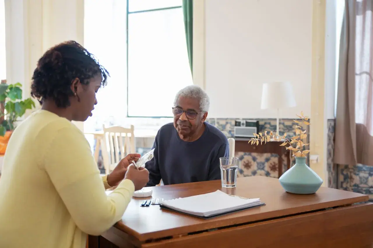 Une professionnelle échange avec une personne accompagnée, dossier ouvert sur la table.