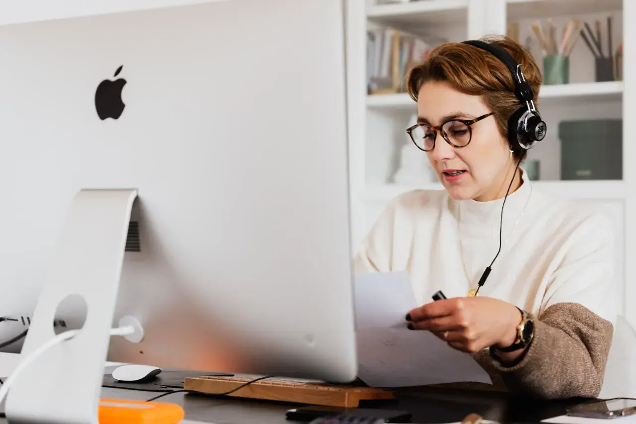 Une professionnelle suit un module en ligne avec un casque, devant son ordinateur.