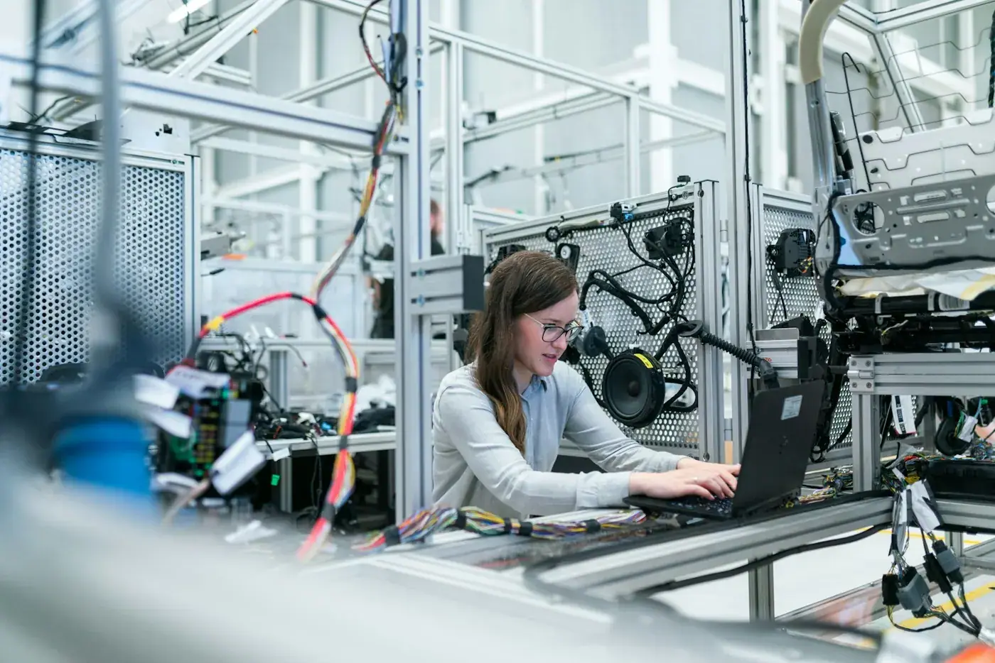 Une ingénieure travaille sur son ordinateur portable au milieu d'un banc d'essai industriel.