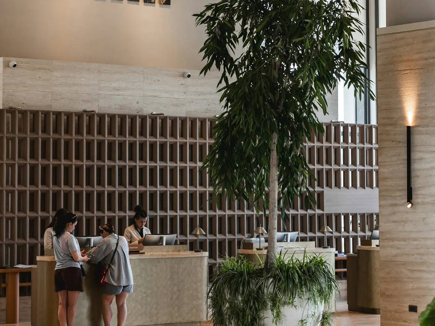 Des voyageurs à la réception d'un hôtel, pris en charge par l'équipe d'accueil.