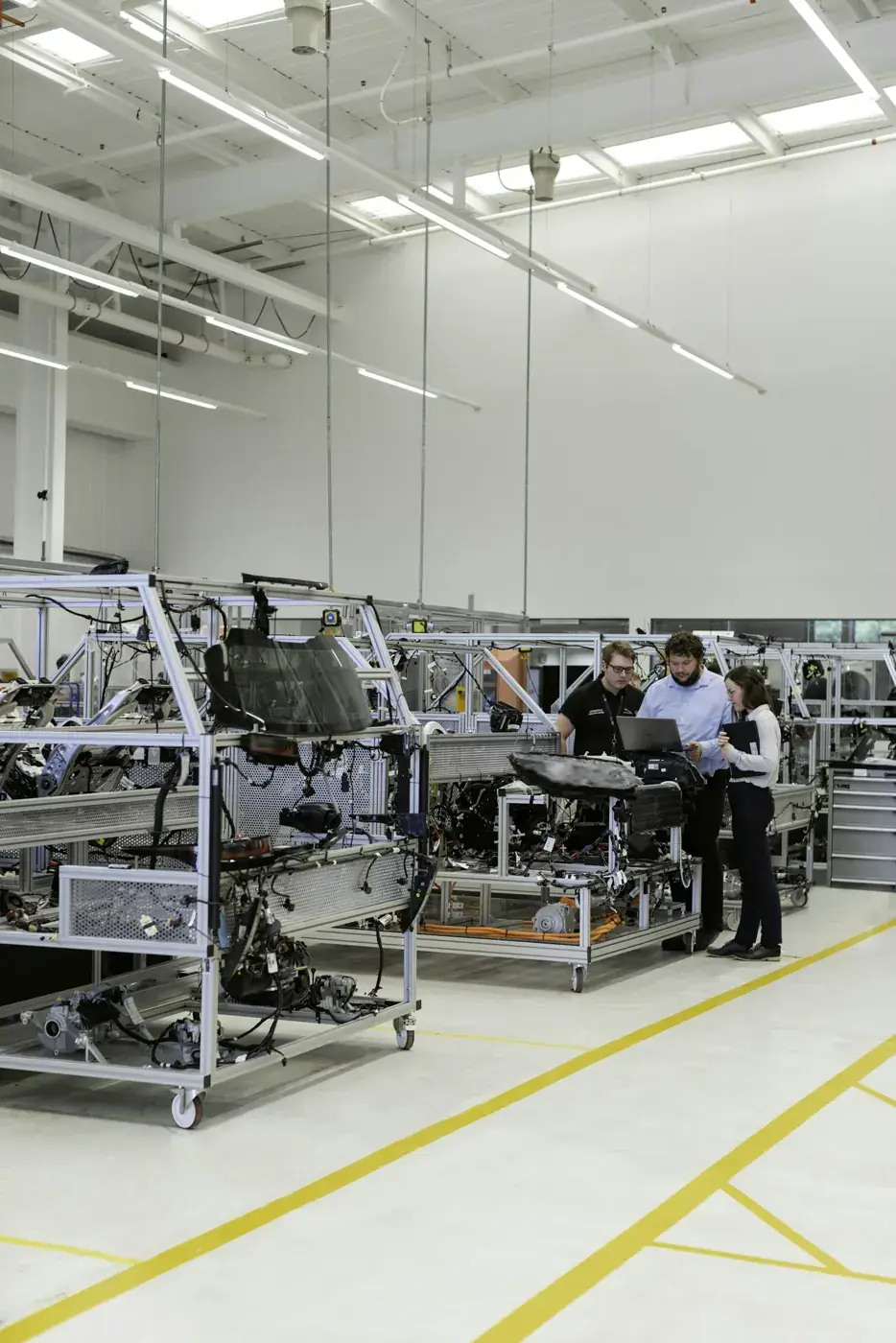 Des ingénieurs échangent au milieu d'un atelier de production automobile.