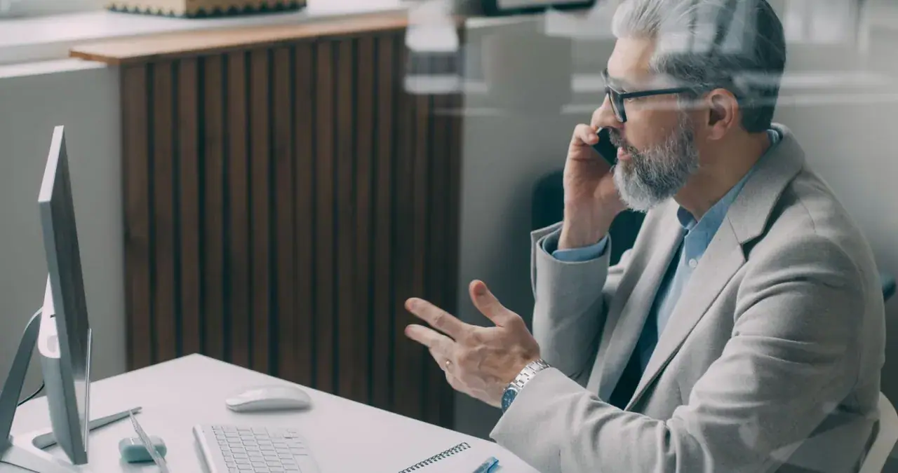 Un commercial au téléphone avec un client, à son bureau.